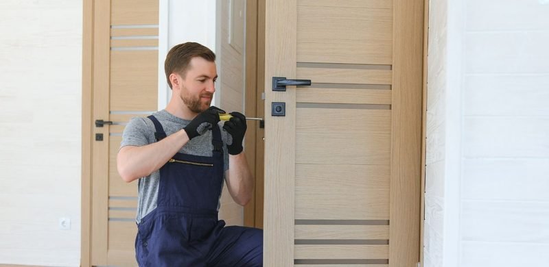 Handyman installing a door lock with a screwdriver